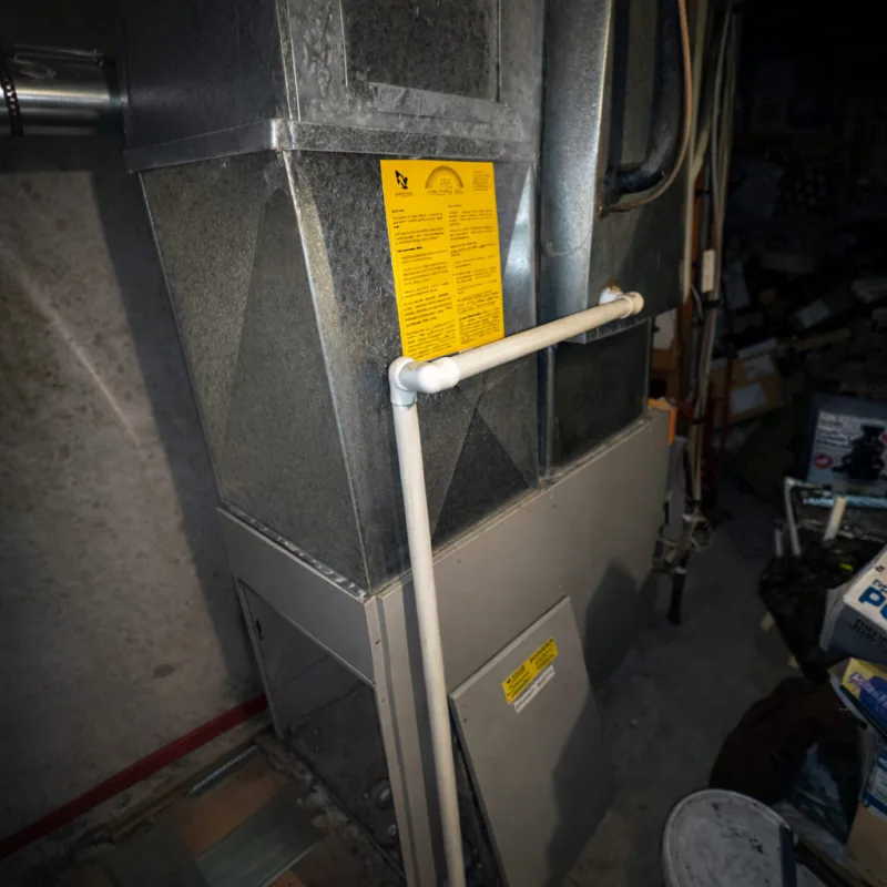 Fournaise au gaz avec tuyau PVC blanc et étiquette jaune attachée sur le conduit en métal