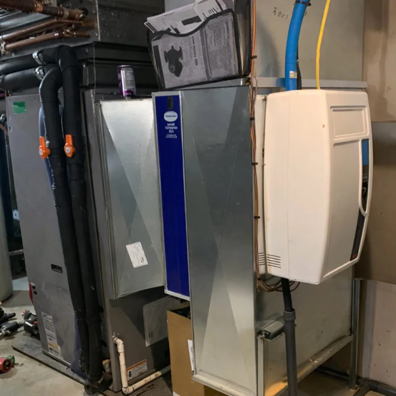 Installations HVAC avec conduits métalliques, tubes noirs isolés, et boîtier blanc fixé au mur