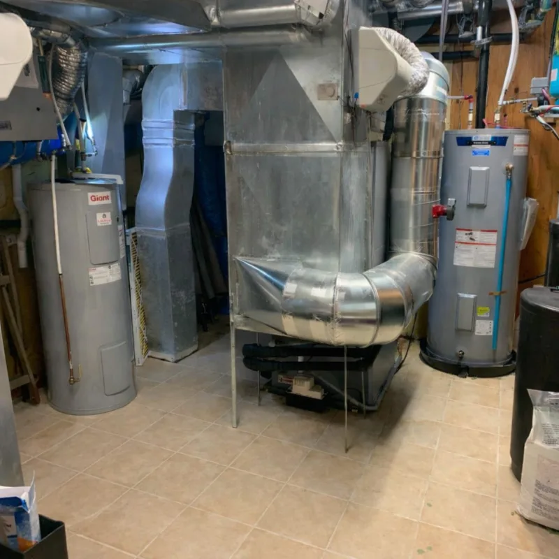 Salle mécanique avec chauffe-eau, conduits d'aération et appareils HVAC dans sous-sol carrelé