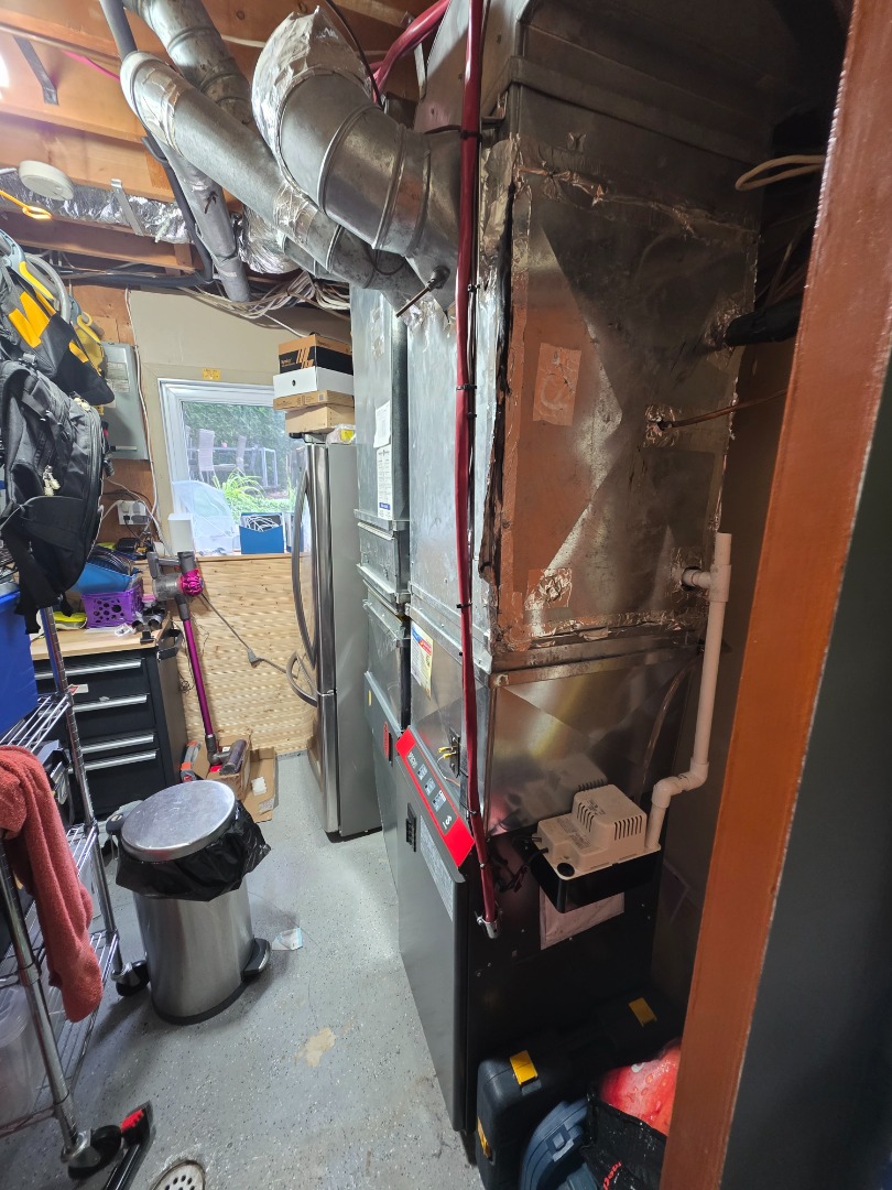 Un système de chauffage central avec conduits en métal et tuyaux isolés dans un sous-sol.