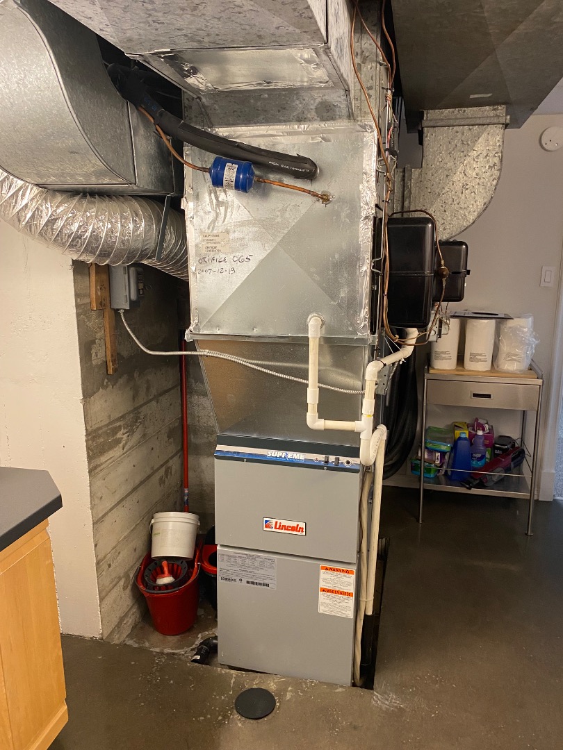 Un système de chauffage central avec conduits en métal et tuyaux isolés dans un sous-sol.