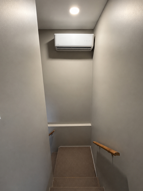 Chambre avec appareil gris, tuyaux noirs et porte blanche à l'arrière