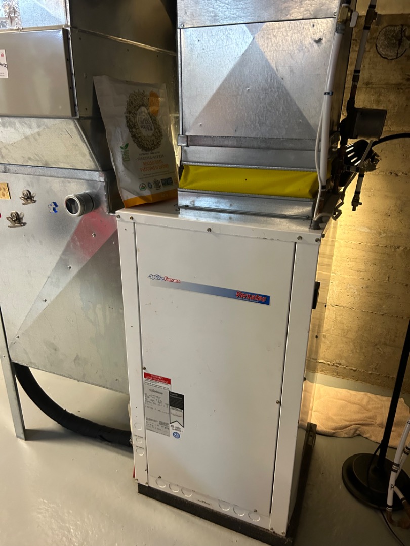 Un système de chauffage central avec conduits en métal et tuyaux isolés dans un sous-sol.