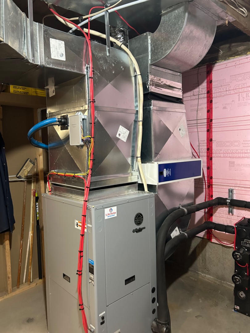 Un système de chauffage central avec conduits en métal et tuyaux isolés dans un sous-sol.