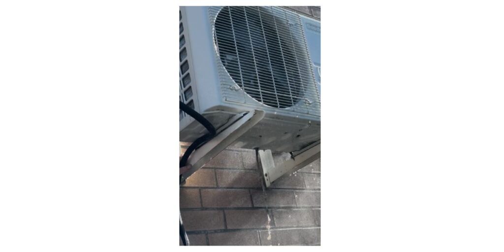 Unité extérieure de thermopompe fixée sur des supports devant un mur de brique